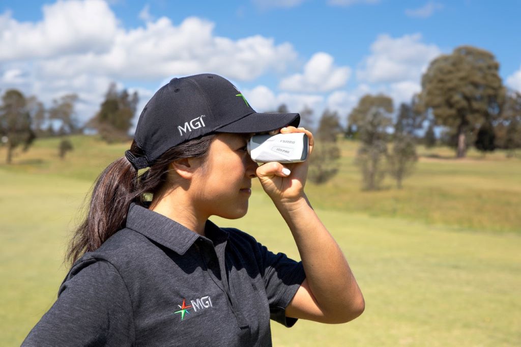 Golfer using a golf rangefinder to measure distance before a shot